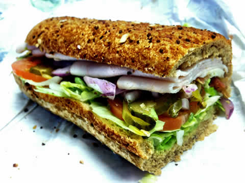 A highly saturated, wide angle photograph of a Subway veggie-delite sandwich.