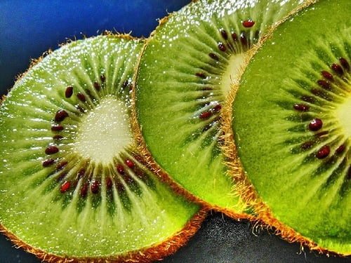 A closeup view of kiwifruit sliced crosswise, revealing a star pattern