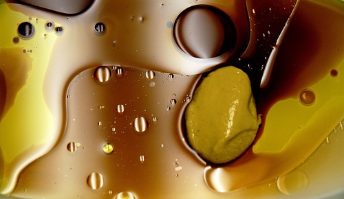Droplets of oil and balsamic vinegar swirling to create a fluid, beautiful scene that looks like cells under a microscope.