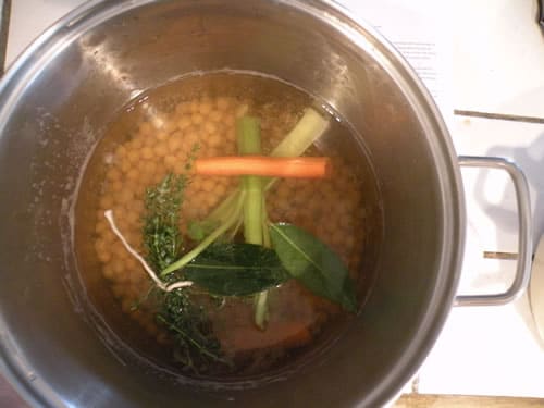 Chickpeas, herbs, and vegetables in stock pot