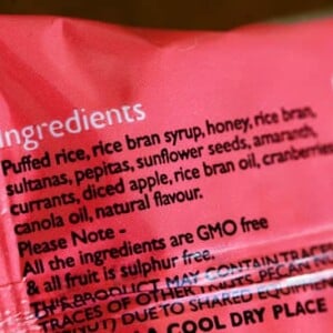 The back of a processed food package, showing an ingredients list with multiple types of sugar: rice bran syrup and honey.