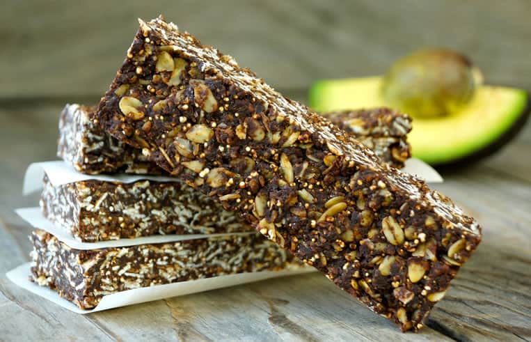 Stack of Chocolate Avocado Breakfast Bars with an avocado in the background