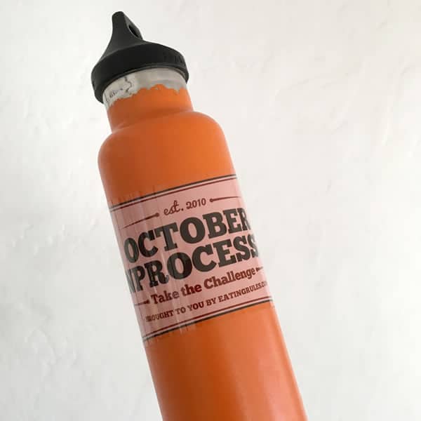 An October Unprocessed sticker on an orange water bottle