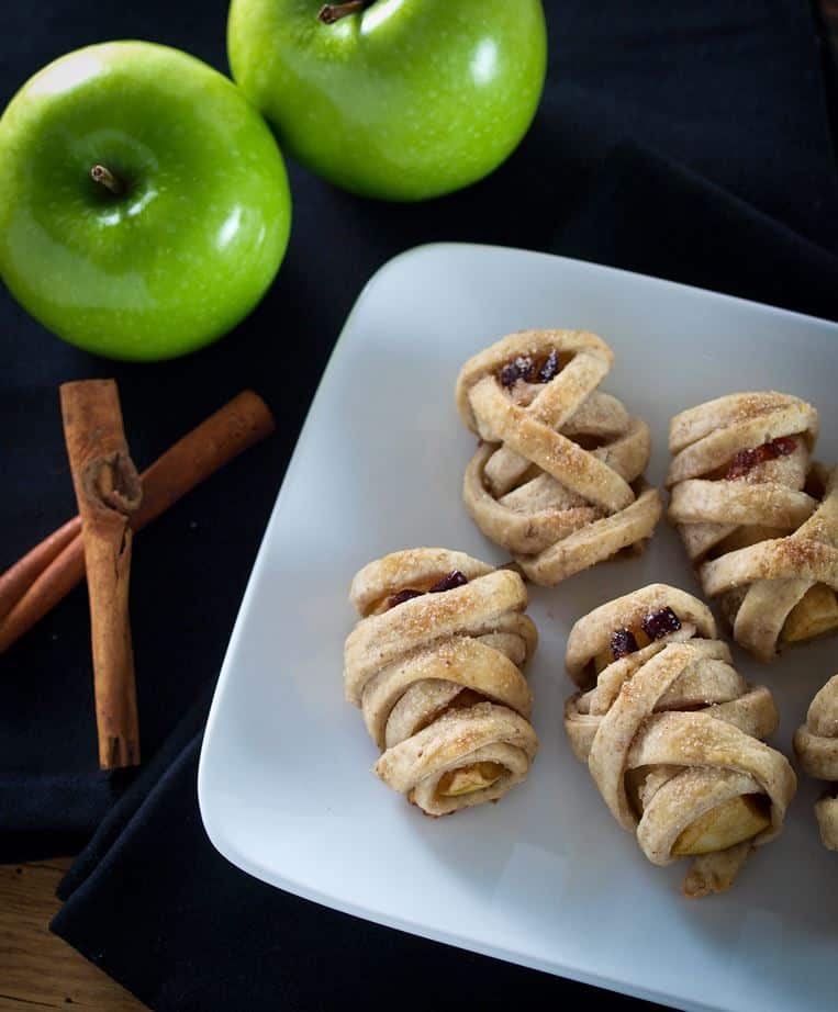 Overhead view of mummy dumplings on a plate with apples and cinnamon