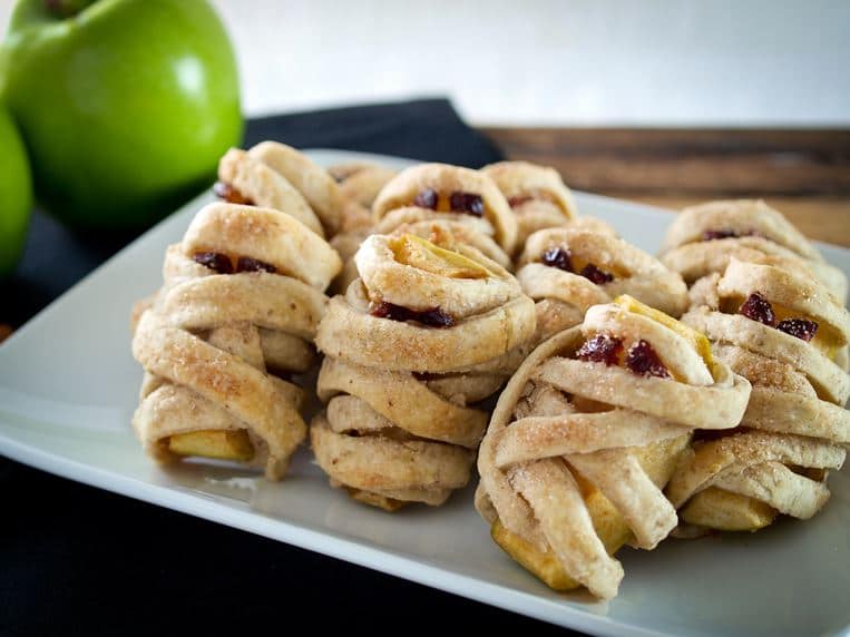 Mummy dumplings standing up on a plate with green apples in the background