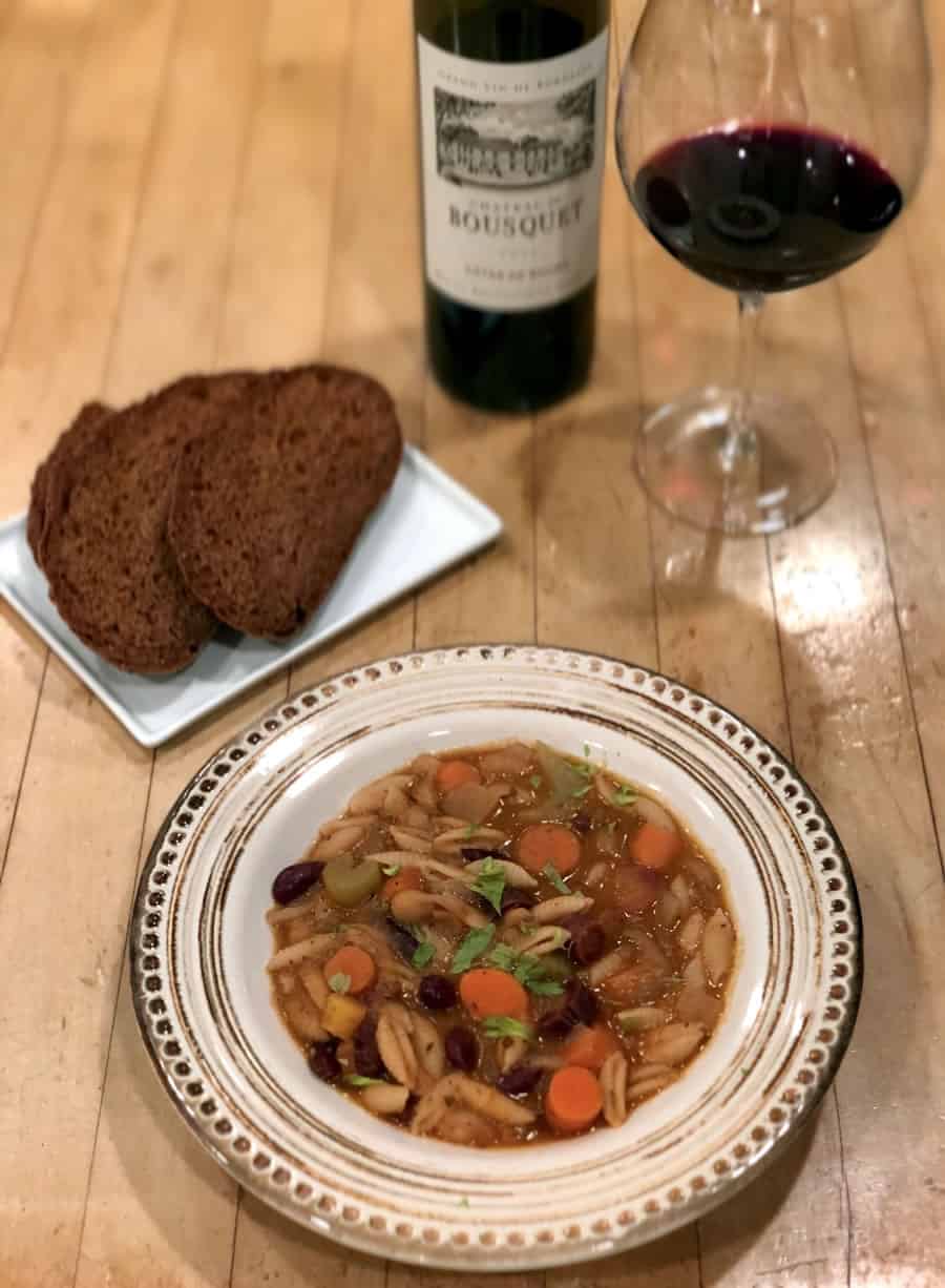 Bowl of minestrone soup with slices of pumpernickel bread