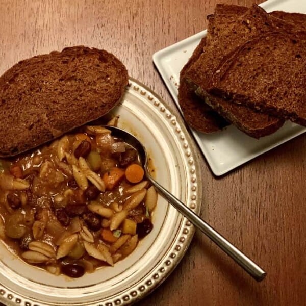 Bowl of minestrone soup with slices of pumpernickel bread