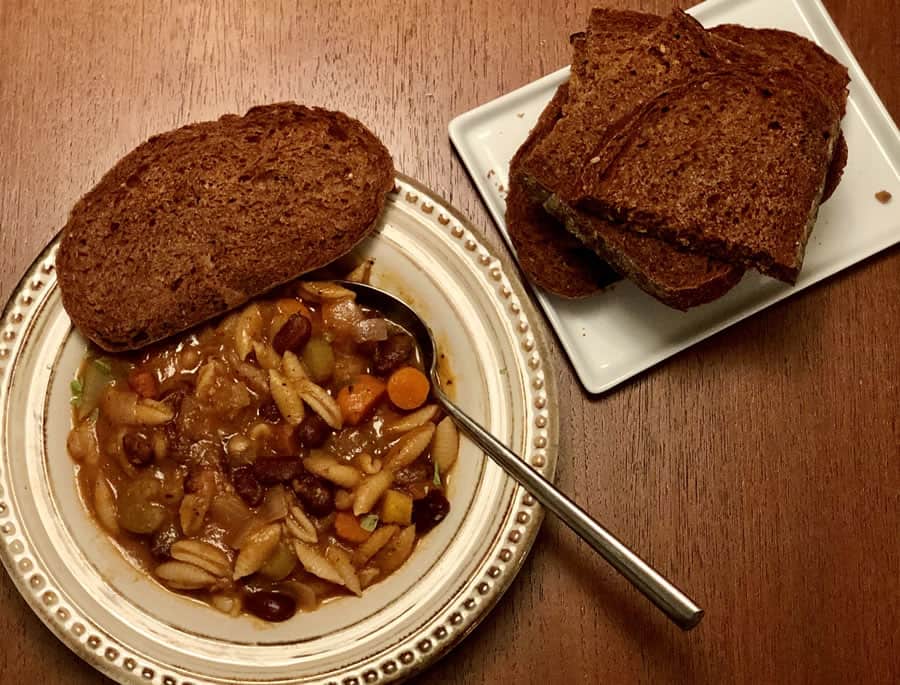 Bowl of minestrone soup with slices of pumpernickel bread