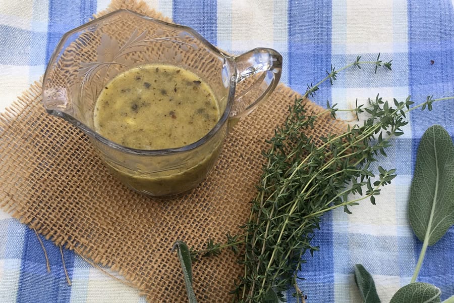 Salad dressing in a serving glass, with fresh herbs